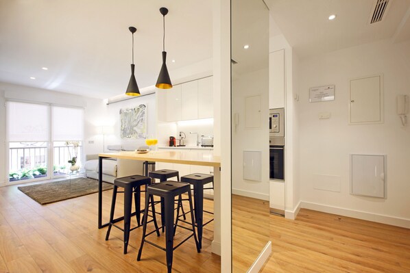 A modern kitchen with a central island, bar stools, pendant lighting, and a view of the outdoors.