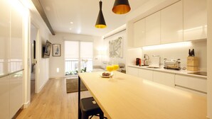 A modern kitchen with white cabinets, a wooden countertop, and two pendant lights. - Gran Via Boutique (Madrid)