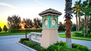 A sign for 'The Retreat' with a stone base and green accents, surrounded by well-maintained landscaping and palm trees. - Luxury Championsgate Villa (Davenport)