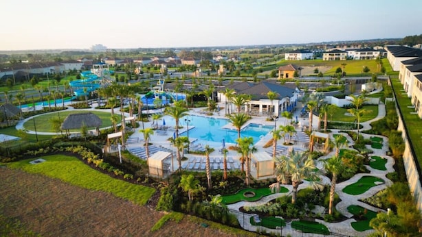 A resort with multiple swimming pools, palm trees, and a golf course. - Luxury Championsgate Villa (Davenport)