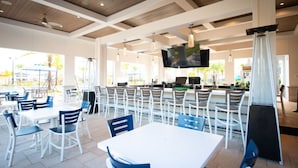 A restaurant with outdoor seating, a bar area, and a TV screen. - Luxury Championsgate Villa (Davenport)