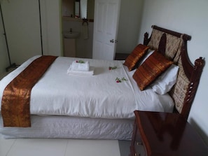 Una cama bien hecha con sábanas blancas y un plaid marrón decorativo.
