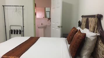 A hotel room with a bed, a bathroom with a sink, and a door leading to another room.