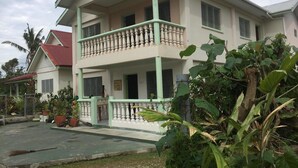 A two-story house with a balcony, surrounded by greenery and a paved area. - Malau Lodge (Nuku'alofa)