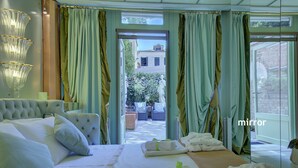Een hotelkamer met een groot bed, uitzicht op de binnenplaats en een spiegel.