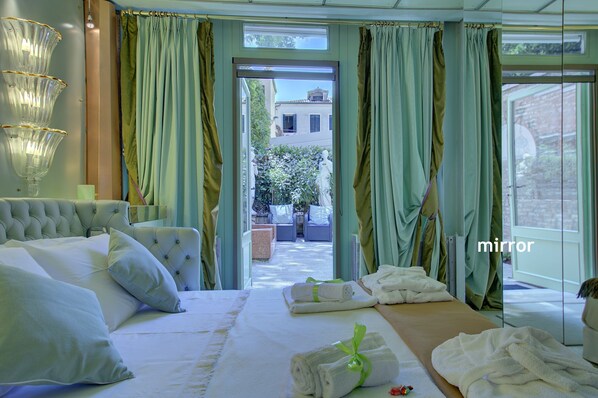 Ein Hotelzimmer mit einem großen Bett, Blick auf den Innenhof und einem Spiegel.