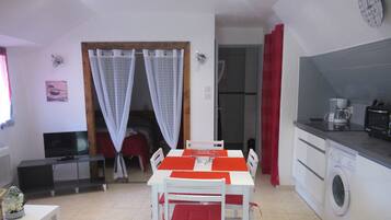 A compact living space with a dining area, kitchenette, and a TV.