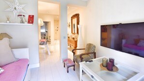 Una sala de estar con sofá, sillón, televisión y una mesa con objetos decorativos.