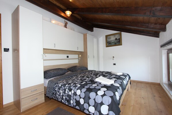 A bedroom with a bed, wooden wardrobe, and a painting on the wall. - CUVI Holiday House with Garden (Rovinj)
