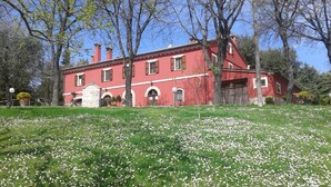 A red building with a stone entrance, surrounded by trees and a field of white flowers. - country holiday home - Serrungarina (Serrungarina)