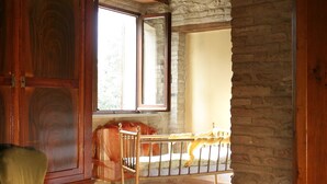 A room with a stone archway, a wooden chair, a wooden bench, and a view of a balcony. - country holiday home - Serrungarina (Serrungarina)