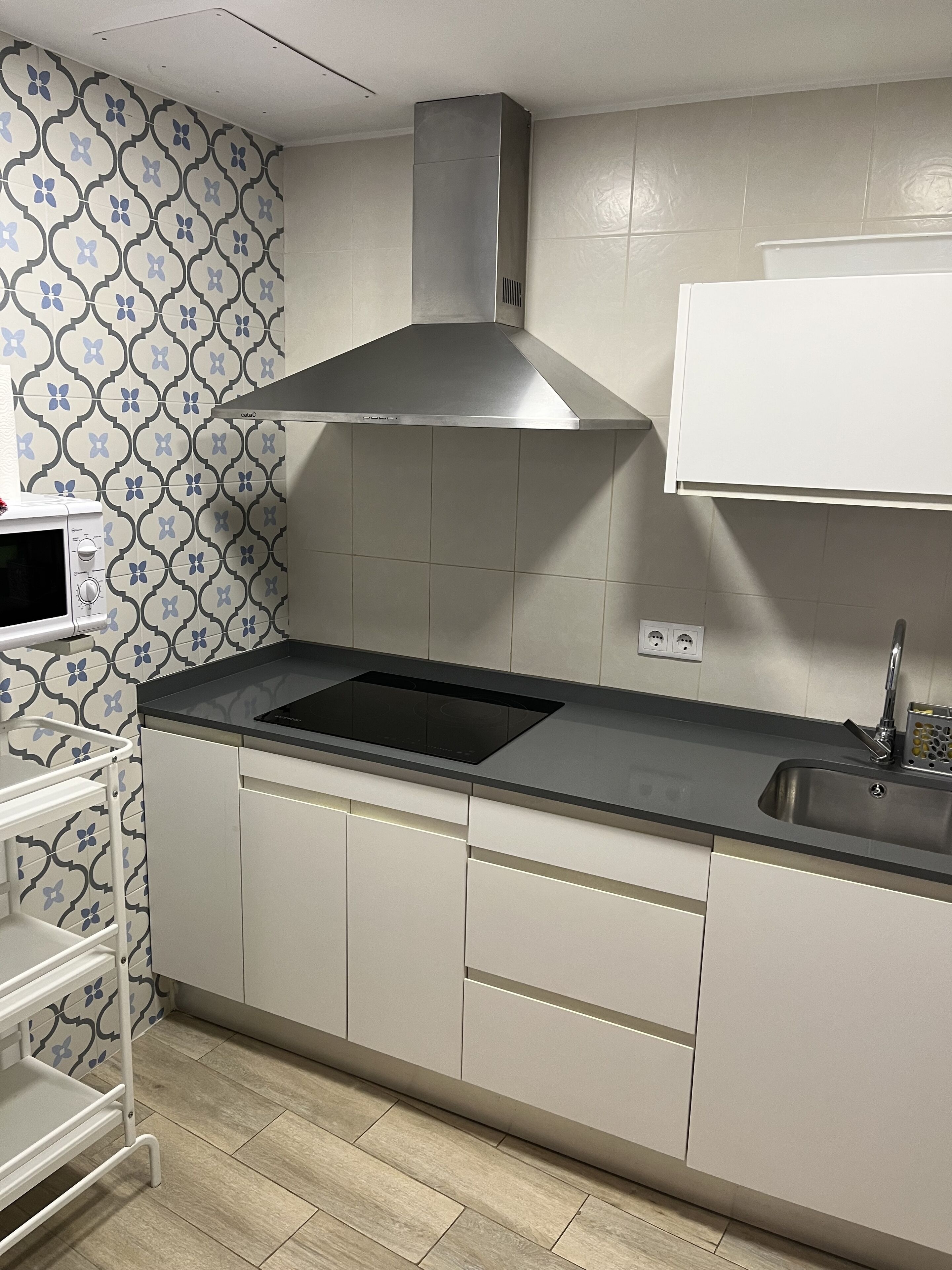 Une cuisine moderne dotée d’une cuisinière intégrée, d’une hotte en acier inoxydable et d’un meuble blanc agrémenté d’un pare-feu décoratif.