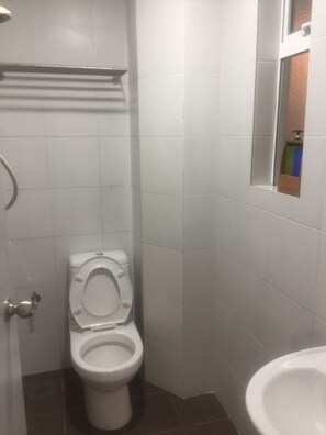 Un baño pequeño y limpio con azulejos blancos, un inodoro y un lavabo.