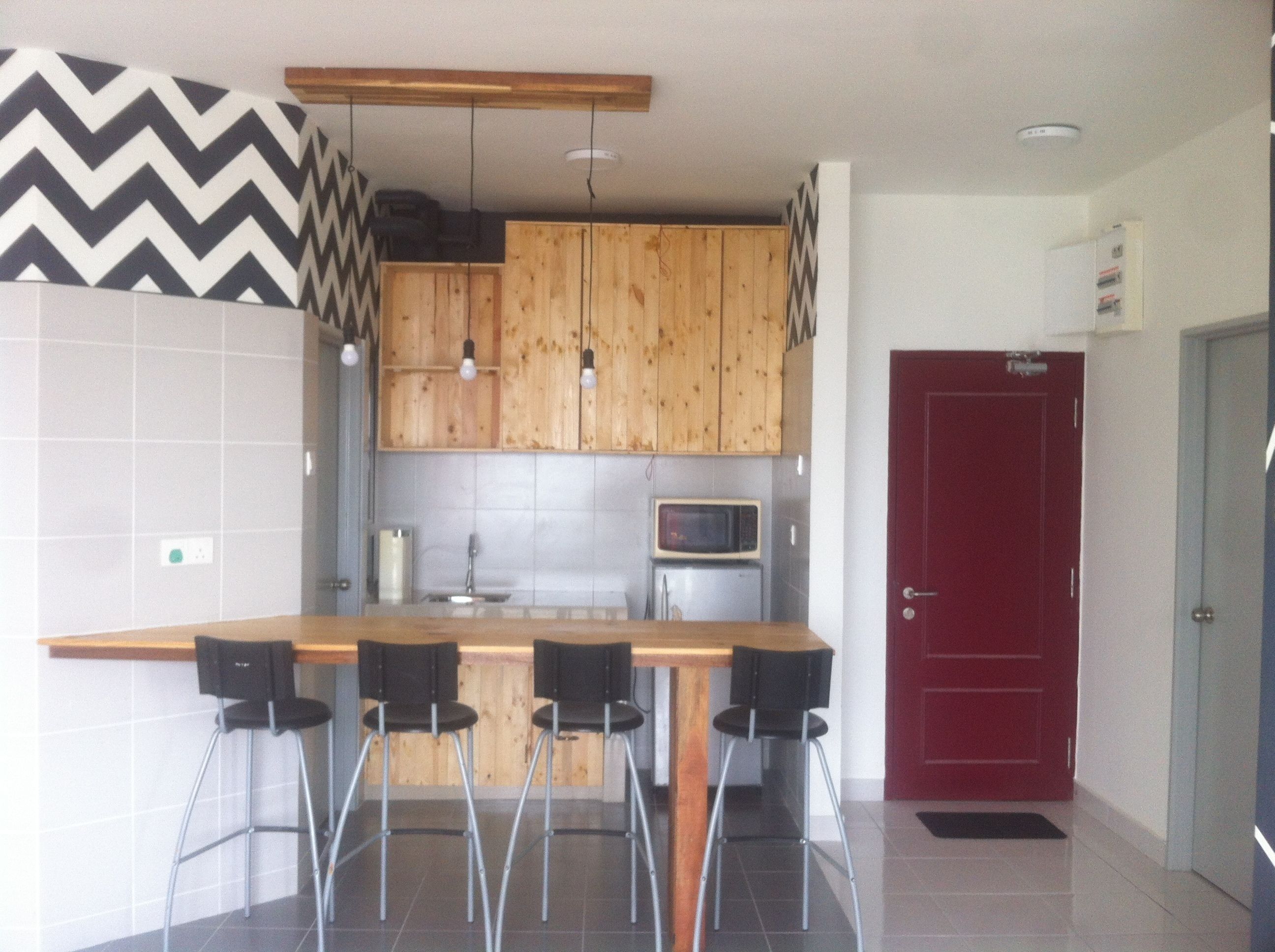 Una cocina moderna con armarios de madera, microondas integrado y una puerta roja.