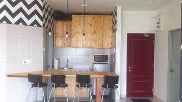 Una cocina moderna con armarios de madera, microondas integrado y una puerta roja.
