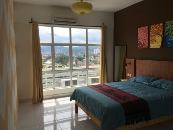 Un dormitorio con una ventana grande, una cama, una mesita de noche y un espejo.