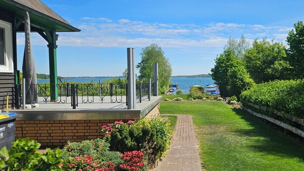 A garden with a paved pathway, a gazebo, and a view of a lake.