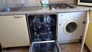 Une cuisine compacte équipée d’un lave-vaisselle, d’une machine à laver, d’une cuisinière et d’un évier.