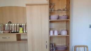 Une cuisine de taille réduite, avec un meuble en bois, une table à manger recouverte d’une nappe à motifs floraux et une chaise.