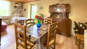 A dining area with a wooden table, chairs, a vase with flowers, and a cabinet with wine bottles. - Winetourism in the heart of Bordeaux (Margueron)