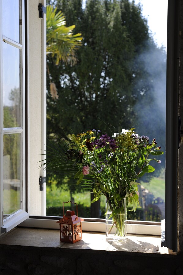 Ein Fenster mit einem Blumenarrangement und einer Laterne auf der Fensterbank.