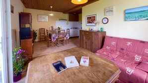 A cozy living room with a wooden ceiling, a dining area with chairs and a table, and a kitchen in the background. - Winetourism in the heart of Bordeaux (Margueron)