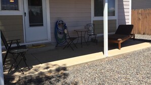 A covered patio with outdoor furniture, including a lounge chair and dining chairs. - Central Cedaredge Cottage (Cedaredge)