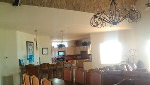 Un'ampia zona pranzo con tavolo e sedie in legno, una cucina sullo sfondo e un lampadario.