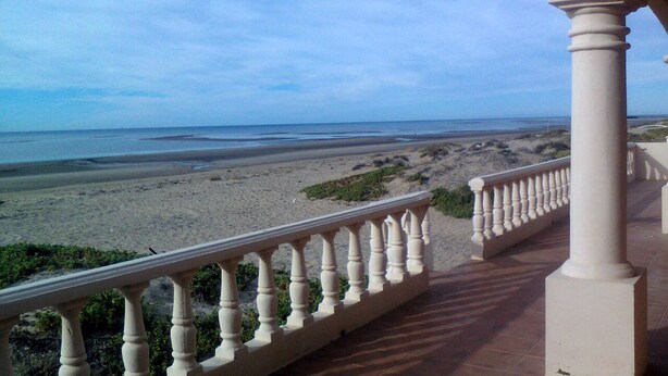 Un balcone con vista su una spiaggia sabbiosa e l'oceano.