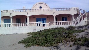 Una proprietà fronte spiaggia con un balcone curvo, diverse finestre e una cupola centrale.