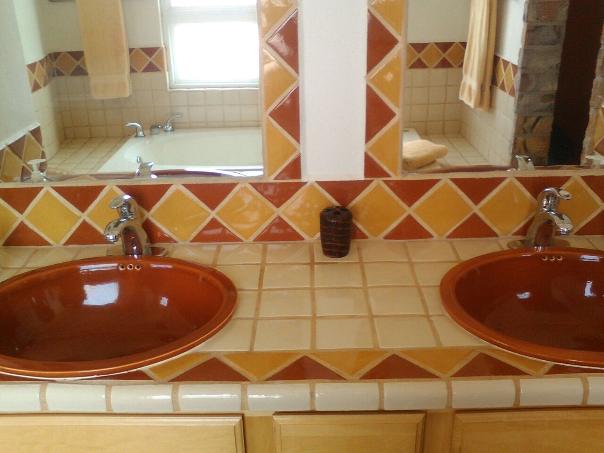Une salle de bain avec deux lavabos, un miroir et une fenêtre.