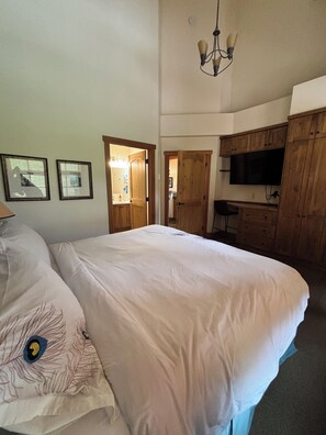 Ein Schlafzimmer mit einem großen Bett, einem Holzschrank, einem Fernseher und einer Kristallleuchtre.