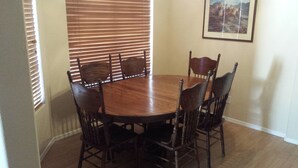 A dining room with a round wooden table surrounded by six chairs.