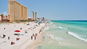 Una playa con varios edificios de hotel, incluido un edificio alto de varios pisos con balcones.