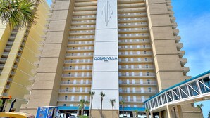 Un hotel de gran altura llamado Oceanvilla, con múltiples balcones, un letrero vertical llamativo y una entrada con techo azul.