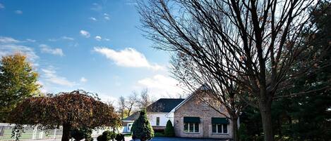 A residential house with a brick exterior, a well-maintained lawn, and a tree in the foreground.