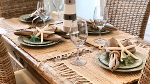 Una mesa de comedor dispuesta con platos, servilletas, estrellas de mar y una lámpara en forma de faro como centro de mesa.