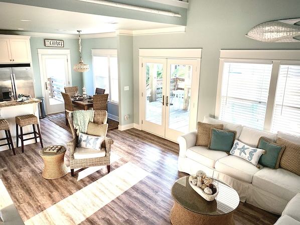 A spacious living area with a kitchen, dining area, and a large sliding glass door leading to a deck.