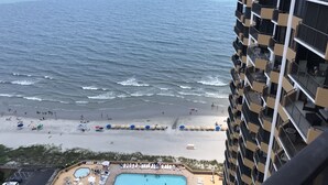 Un hotel di grandi dimensioni affacciato su una spiaggia con piscina e ombrelloni.