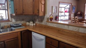 Cuina amb armaris de fusta, un rentaplats i una finestra amb vista a l'exterior.