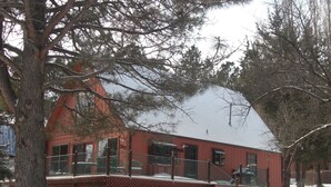 Un edifici vermell amb un teulat cobert de neu i un balcó de fusta.