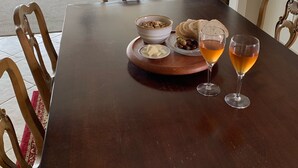 A dining table with a tray of food, two glasses of wine, and a bowl of nuts.