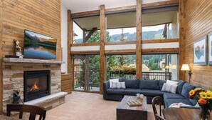 A spacious living room with a stone fireplace, a large sofa, and a dining area.