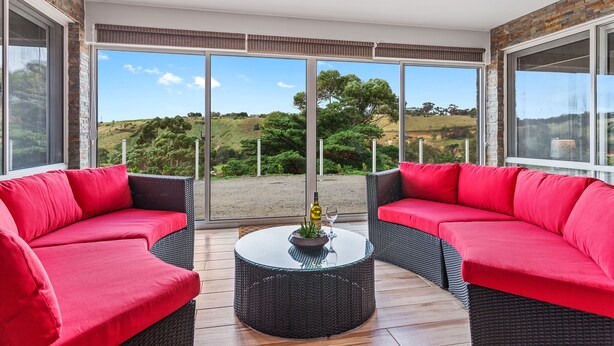 A modern balcony with wicker furniture and a glass table, offering a scenic view of the countryside. - Bulla Hill Villas- Melbourne Airport (Bulla)