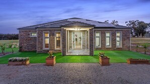 A modern house with a stone facade, large windows, and a well-maintained lawn. - Bulla Hill Villas- Melbourne Airport (Bulla)