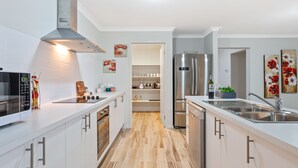 A modern kitchen with white cabinets, stainless steel appliances, and a wooden floor. - Bulla Hill Villas- Melbourne Airport (Bulla)