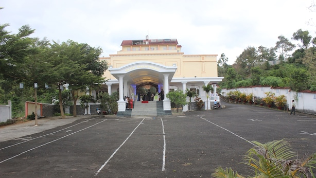 A building with a covered entrance, a parking lot, and surrounding greenery. - Memories Hotel (B'Lao)