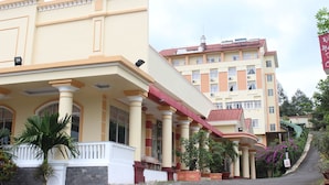A multi-story hotel with a beige facade, red accents, and a balcony with a white railing. - Memories Hotel (B'Lao)