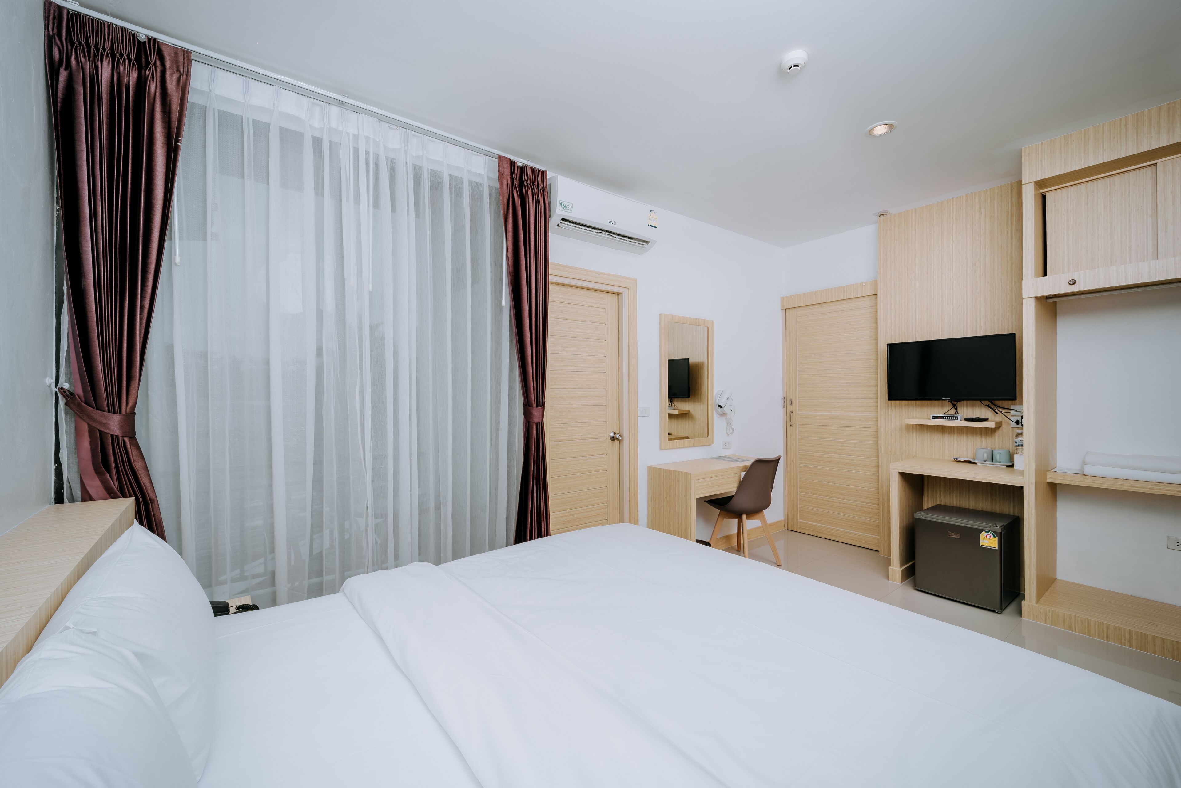 Une chambre d’hôtel comprenant un lit, un bureau, une chaise, un téléviseur et une armoire.
