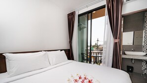 A hotel room with a large bed, a bathroom with a sink and mirror, and a balcony with a table and chairs. - Circle Inn Ao Nam Mao (Krabi)